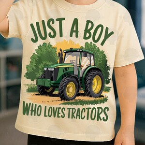 May include: A light yellow t-shirt with the text "JUST A BOY WHO LOVES TRACTORS" and a graphic of a green tractor. The tractor has yellow wheels and is set against a backdrop of trees and a yellow sun.