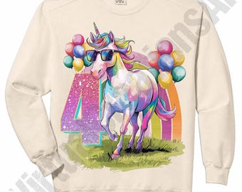 May include: Cream-colored sweatshirt featuring a colorful unicorn wearing sunglasses, with a rainbow and balloons. The number "4" is displayed in a glittery font. The design is printed on the front of the sweatshirt.