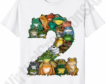 May include: White t-shirt featuring a large number "2" composed of various colorful frog illustrations. The frogs are in shades of green, brown, orange, and blue, creating a playful and eye-catching design. The shirt is made of a soft, comfortable material.