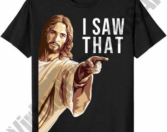 May include: Black t-shirt featuring a graphic of Jesus pointing with the text "I SAW THAT" in white block letters. The illustration depicts Jesus with long brown hair and a beard, wearing a white robe.
