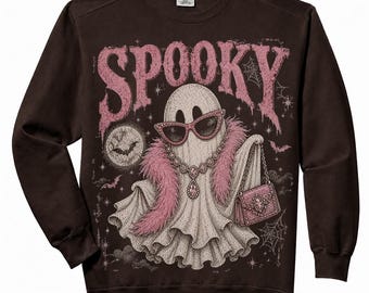 May include: A dark brown long-sleeve sweatshirt featuring a graphic of a ghost wearing pink cat-eye sunglasses, a pink feather boa, and a jeweled necklace. The ghost holds a pink handbag. The text SPOOKY appears above in pink, with bats, stars, and spiderwebs.