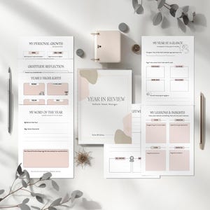 May include: A neutral-toned planner and journal set, ideal for reflection. The planner, titled "Year in Review", features pages for personal growth, yearly highlights, and insights. Two pens and decorative items are also visible in the image.