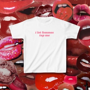 May include: White t-shirt with pink text that reads "i let femmes top me".