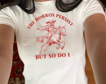 The Horrors Persist But So Do I Baby Tee Funny Raccoon Shirt Trendy Women's Shirt Custom 90s Style Graphic TShirt Gifts For Her Cowboy Meme
