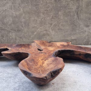 Könnte beinhalten: Eine handgefertigte, organisch geformte Holzschale in einem satten, dunkelbraunen Farbton. Die Schale hat ein einzigartiges, asymmetrisches Design mit mehreren gebogenen Abschnitten, die die natürliche Holzmaserung hervorheben. Dieses dekorative Stück eignet sich zum Servieren oder Ausstellen.