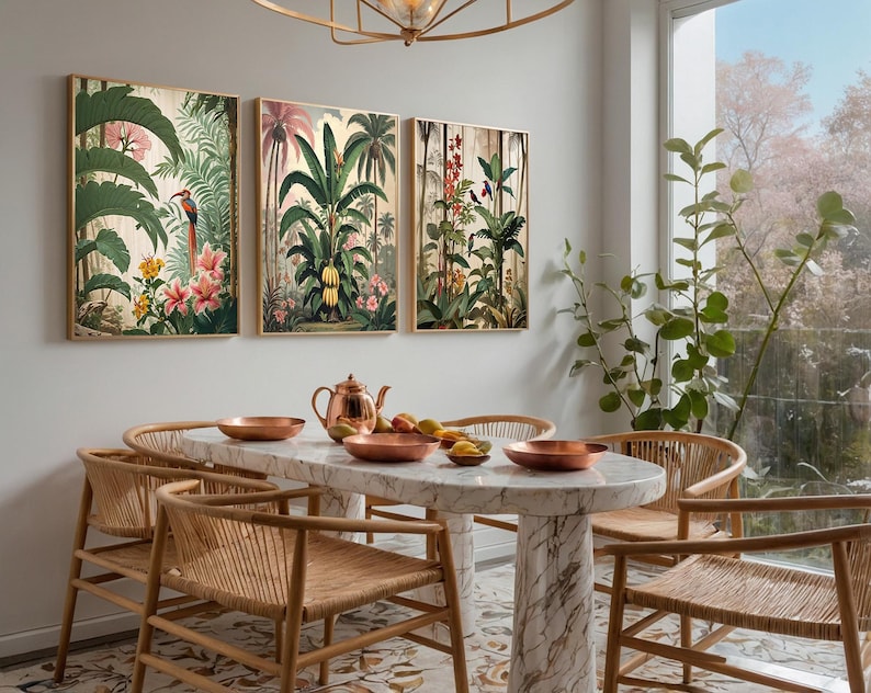 Three framed botanical art prints showcasing tropical scenes with green foliage, pink flowers, and birds. A marble dining table with copper bowls and woven chairs are set in a dining room. The table is approximately 150 cm long.