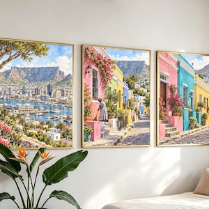 Peut inclure: Un ensemble de trois cadres muraux représentant des scènes colorées du Cap. L'image de gauche montre un port avec la montagne de la Table en arrière-plan. Les images centrale et droite illustrent des maisons colorées et des rues pavées.