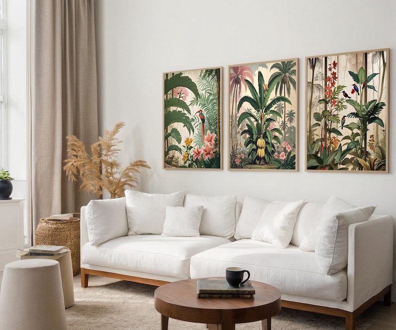 Three framed botanical prints depicting tropical scenes with palm trees, flowers, and birds. The artwork has a vintage style with a warm colour palette. The prints are displayed above a white sectional sofa in a living room setting.