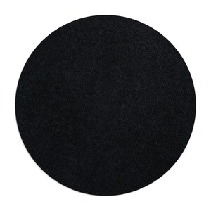 Puede incluir: Un posavasos redondo negro con una superficie texturizada.