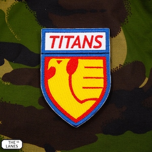 May include: An embroidered patch in blue and red with a yellow bird design and the word "TITANS" in white lettering.