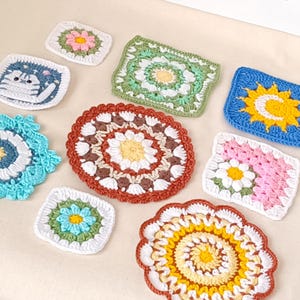 Puede incluir: Una colección de posavasos de ganchillo hechos a mano y coloridos en varias formas y diseños. Los posavasos presentan patrones florales, formas geométricas y un diseño de gato. Los colores incluyen azul, verde, rosa, amarillo y blanco.