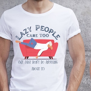 Pode incluir: Duas pessoas vestindo camisetas com um gráfico de uma pessoa deitada em um sofá vermelho. O texto nas camisetas diz "Lazy People Care Too (We Just Don't Do Anything About It)"