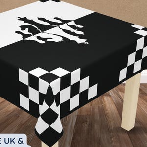 Puede incluir: Un mantel cuadrado con un patrón de cuadros blancos y negros en los bordes y un diseño abstracto en blanco y negro en el centro. El mantel está sobre una pequeña mesa de madera. El texto "Tablecloth Only" es visible.