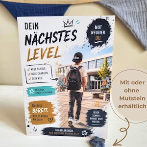 Könnte beinhalten: Eine rechteckige Grußkarte mit einem Foto einer Person mit Rucksack, die auf ein Schulgebäude zugeht. Die Karte enthält deutschen Text wie DEIN NÄCHSTES LEVEL, NEUE SCHULE und DU BIST BEREIT sowie einen kleinen blauen, sternförmigen Stein.