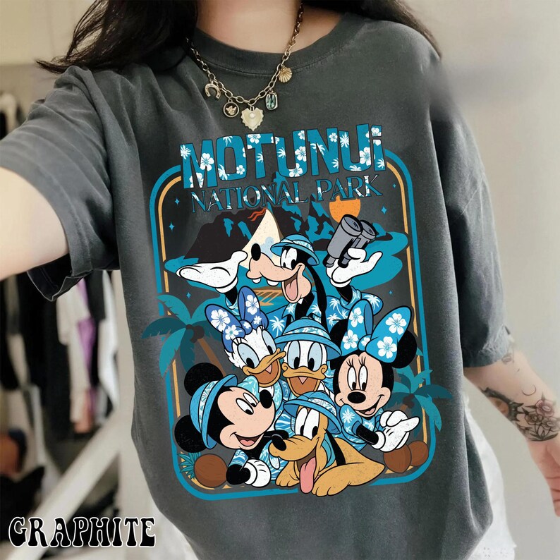 May include: Graphite-colored t-shirt featuring a graphic of Disney characters, including Mickey, Minnie, Donald, Daisy, Goofy, and Pluto. The design includes the text "MOTUNUI NATIONAL PARK" in a blue and white tropical theme.