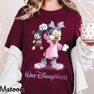 May include: Maroon t-shirt featuring a Minnie Mouse graphic in a pink dress and bow, with Mickey Mouse. The text "Walt Disney World" is printed below the characters. The word "Maroon" is printed at the bottom left.