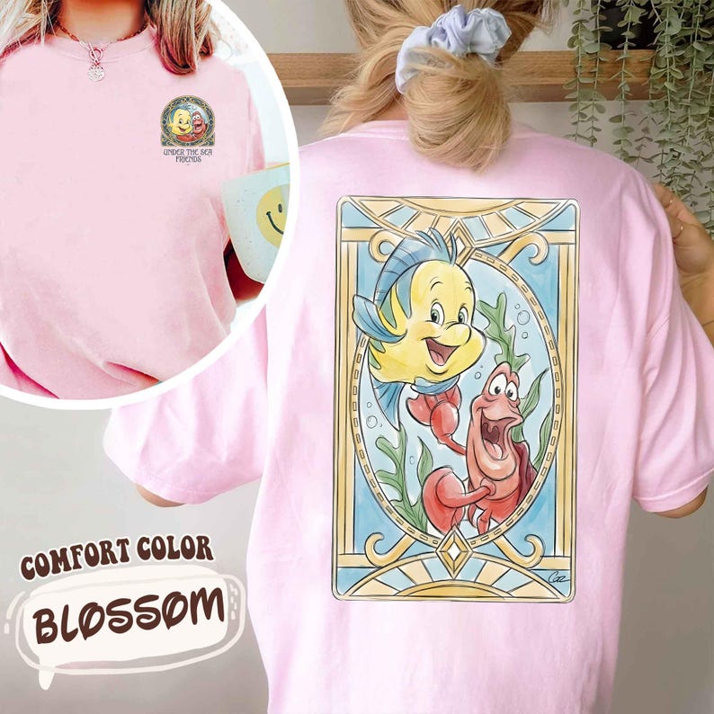 May include: Pink Comfort Color Blossom t-shirt featuring a cartoon graphic of Flounder and Sebastian from The Little Mermaid. The front of the shirt has a small graphic with the text "UNDER THE SEA FRIENDS".