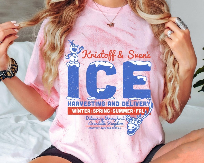 May include: A pink tie-dye t-shirt with a blue and white graphic of Olaf and Sven. The graphic says "Kristoff & Sven's ICE HARVESTING AND DELIVERY WINTER; SPRING SUMMER FALL Delivering throughout Arendelle Kingdom CONTACT SVEN FOR DETAILS".