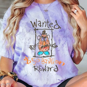 K&ouml;nnte beinhalten: Lilafarbenes T-Shirt im Tie-Dye-Look mit einer Cartoon-Zeichnung von Mr. Potato Head und dem Text "Gesucht 50 Milliarden Belohnung".