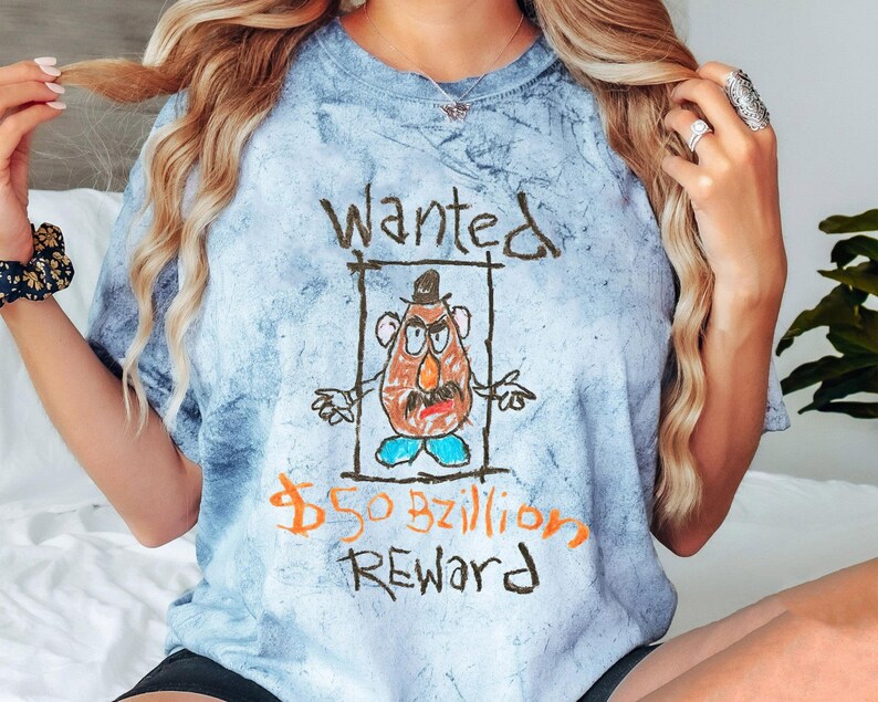 K&ouml;nnte beinhalten: Ein blaues Batik-T-Shirt mit einer Cartoon-Zeichnung von Mr. Potato Head. Die Zeichnung ist im Stil eines Fahndungsplakats mit dem Text "Wanted 50 Milliarden Dollar Belohnung".