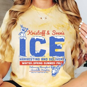 May include: A yellow tie-dye t-shirt with a vintage-style graphic of Olaf from Frozen. The graphic says "Kristoff & Sven's ICE" and "Harvesting and Delivery Winter; Spring Summer Fall" with a reindeer illustration. The text also says "Delivering throughout Arendelle Kingdom Contact Sven for details."