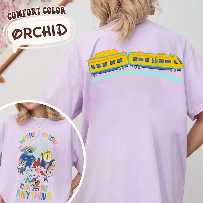 Pu&ograve; includere: T-shirt Orchid Comfort Colors lilla chiaro con un disegno di un treno a fumetti sul retro. La parte anteriore della maglietta presenta una grafica con la scritta "Where Anyone Can Be Anything".