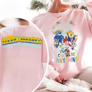 Pu&ograve; includere: Una felpa rosa chiaro con una grafica a cartoni animati colorata e la scritta "WHERE ANYONE CAN BE ANYTHING". Il retro della felpa presenta un disegno di treno giallo e blu. La felpa &egrave; realizzata in materiale morbido.