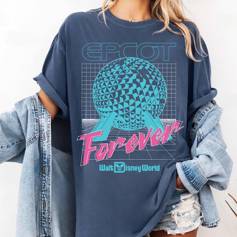 Op de afbeelding: Marineblauwe t-shirt met een grafisch ontwerp. Het heeft het woord "EPCOT" boven een geometrische bol en het woord "Forever" in roze en wit, met "Walt Disney World" eronder.