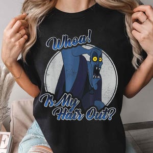 Puede incluir: Camiseta negra con un gr&aacute;fico desgastado de un personaje de dibujos animados azul con ojos amarillos y el texto "Whoa! Is My Hair Out?" en una fuente caprichosa. El dise&ntilde;o est&aacute; dentro de un c&iacute;rculo blanco.