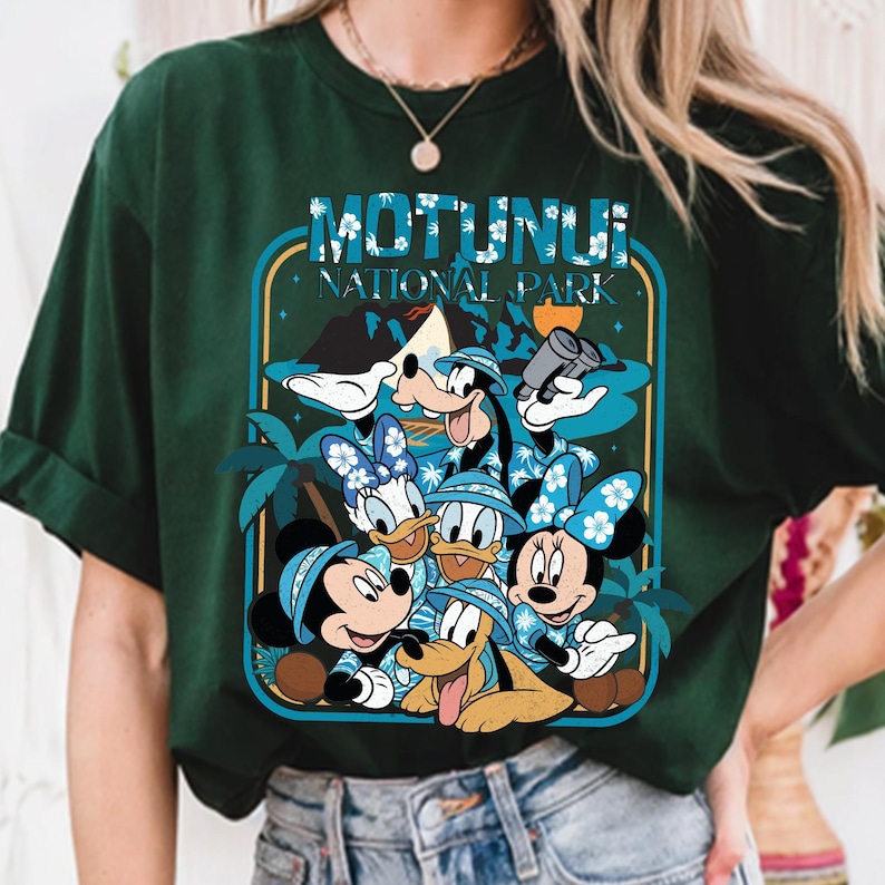 May include: Dark green t-shirt featuring a graphic of Disney characters, including Mickey, Minnie, Donald, Daisy, Goofy, and Pluto, in Hawaiian shirts and hats. The shirt has the text "MOTUNUI NATIONAL PARK" in a blue and white design.