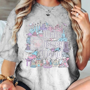 May include: Grey tie-dye t-shirt with a pastel graphic of the Walt Disney World logo and park icons. The design includes castles, rockets, and other attractions in pink, blue, and purple.