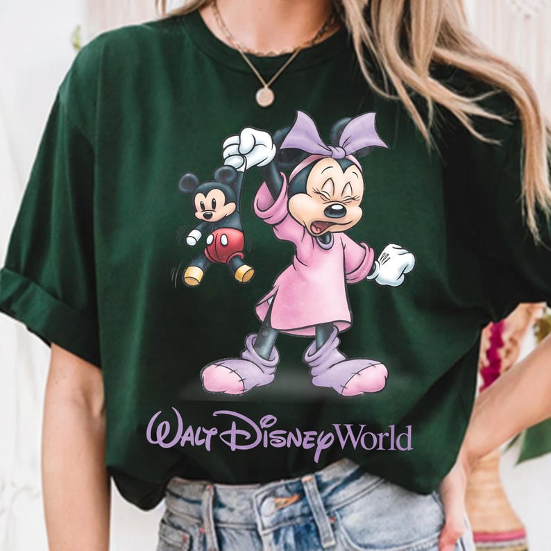 May include: Dark green t-shirt featuring a cartoon illustration of Minnie Mouse in a pink dress and bow, with Mickey Mouse. The text "Walt Disney World" is printed in a cursive font at the bottom of the shirt.