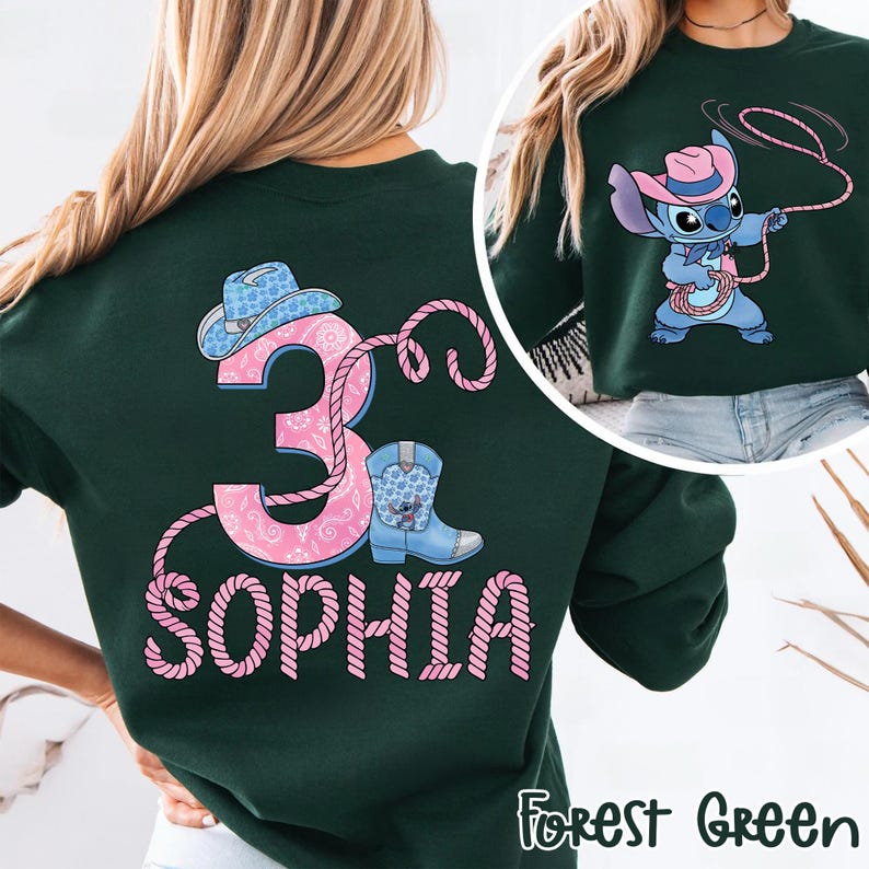 May include: Forest green sweatshirt with a pink and blue cowboy-themed design. Features a number 3, a cowboy hat, a boot, and the name "Sophia" in a rope-like font. The design also includes a cartoon character wearing a cowboy hat and holding a lasso.