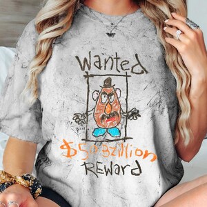 K&ouml;nnte beinhalten: Ein wei&szlig;es T-Shirt mit Used-Look, das eine Comic-Zeichnung von Mr. Potato Head mit dem Text "Wanted 50.000.000.000 $ Reward" zeigt.