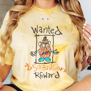 K&ouml;nnte beinhalten: Ein gelbes Batik-T-Shirt mit einem handgezeichneten Fahndungsplakat, auf dem ein Cartoon-Mr. Potato Head abgebildet ist. Das Plakat lautet "Wanted" und "$50 bzillion Reward".