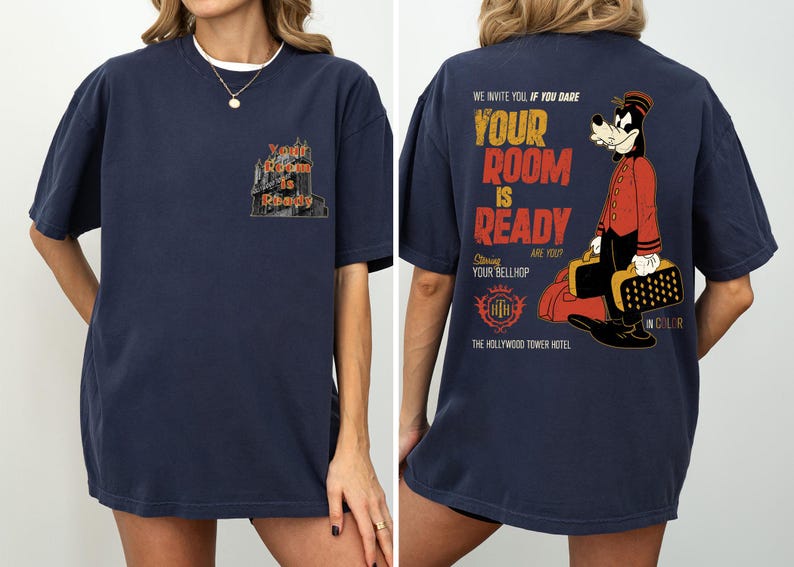 May include: Dark blue t-shirt with a hotel graphic and the text "Your Room is Ready" on the front. The back of the shirt features a cartoon bellhop and the text "We invite you if you dare, Your Room is Ready, Starring Your Bellhop, The Hollywood Tower Hotel."