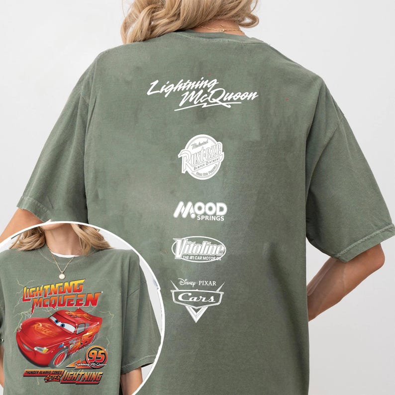 May include: Olive green t-shirt featuring Lightning McQueen from the Disney Pixar Cars movie. The front graphic shows Lightning McQueen with the text "Lightning McQueen" and "95". The back of the shirt has the text "Lightning McQueen" and various logos.