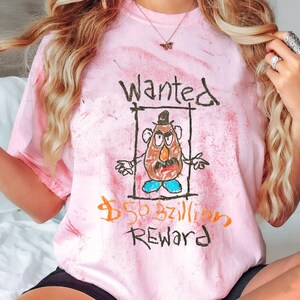 K&ouml;nnte beinhalten: Rosa-farbenes T-Shirt mit Batik-Muster und einer Comic-Zeichnung von Mr. Potato Head sowie dem Text "Wanted $50 bzillion Reward".
