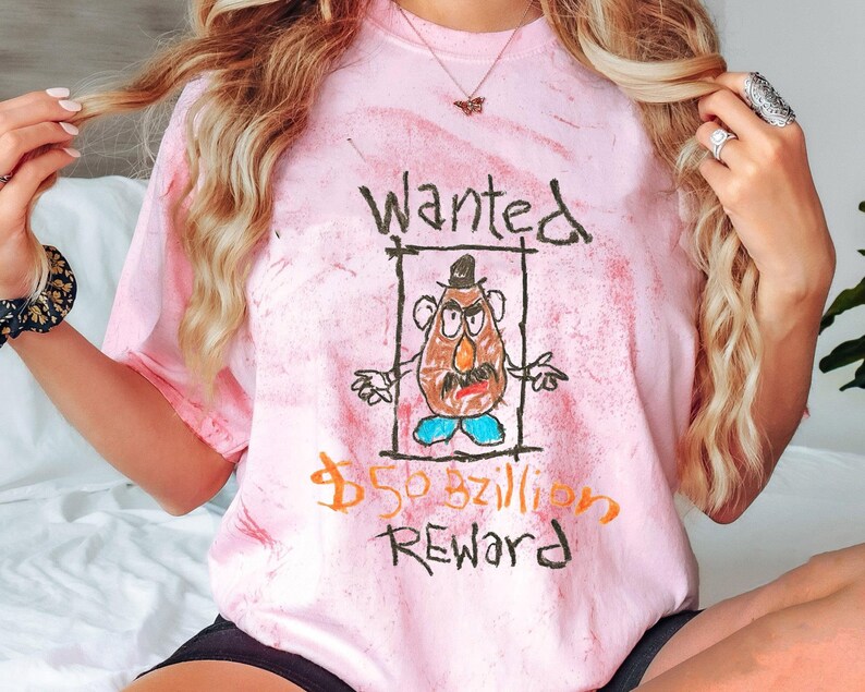 K&ouml;nnte beinhalten: Rosa-farbenes T-Shirt mit Batik-Muster und einer Comic-Zeichnung von Mr. Potato Head sowie dem Text "Wanted $50 bzillion Reward".