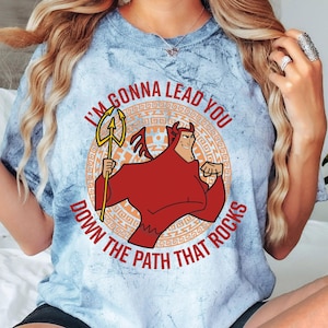 May include: A light blue tie-dye t-shirt with a cartoon image of a red devil holding a trident. The text on the shirt reads "I'm gonna lead you down the path that rocks."