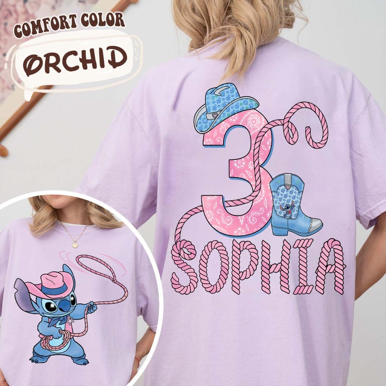 May include: Orchid-colored t-shirt featuring a cartoon character with a cowboy hat and rope. The back of the shirt has a pink number 3, a cowboy hat, a boot, and the name "Sophia" in a rope-like font. The text "COMFORT COLOR" and "ORCHID" are also visible.
