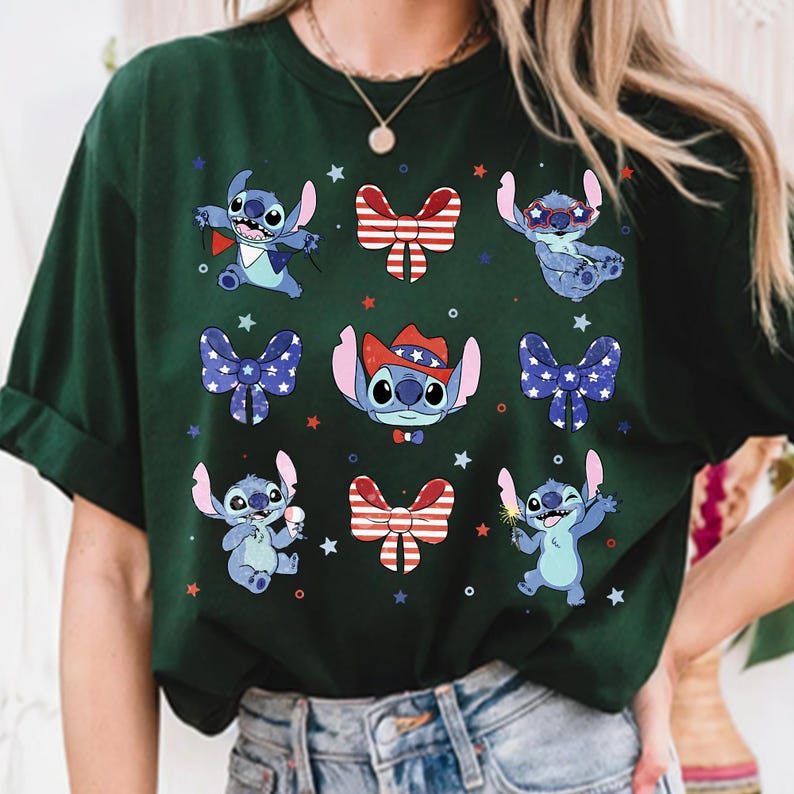 May include: Dark green t-shirt with a repeating pattern of the character Stitch in various poses, adorned with patriotic bow ties and stars. The design incorporates red, white, and blue elements.