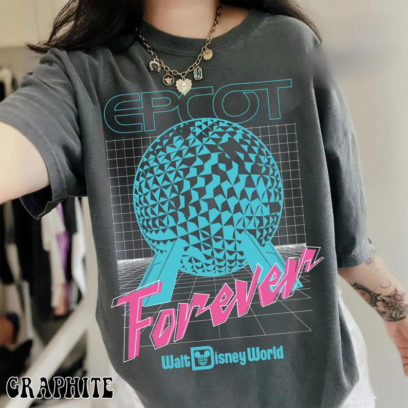 Op de afbeelding: Grafietgrijs T-shirt met een retro design. Het ontwerp toont de tekst "EPCOT Forever" in blauw en roze, een geometrische bol en het Walt Disney World-logo. Het T-shirt is casual en heeft korte mouwen.
