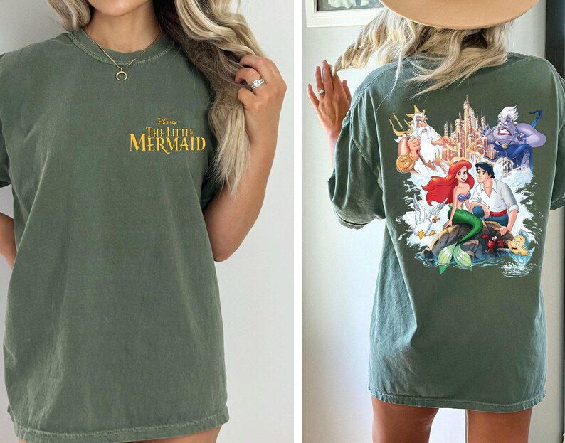 May include: A green t-shirt with a graphic print of Ariel and Prince Eric from Disney's The Little Mermaid. The text "Disney The Little Mermaid" is printed on the front of the shirt.