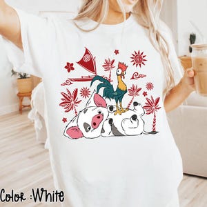 May include: White t-shirt featuring a colorful graphic of a pig, rooster, and boat with red and white accents. The design includes tropical elements like palm trees and suns. The text "Color: White" is at the bottom.