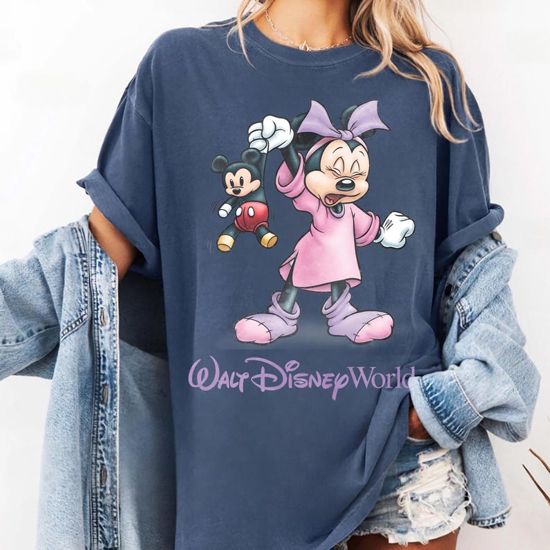 May include: Navy blue t-shirt featuring Minnie Mouse and Mickey Mouse cartoon graphics. Minnie Mouse is wearing a pink dress and bow. The text "Walt Disney World" is printed in a cursive font.