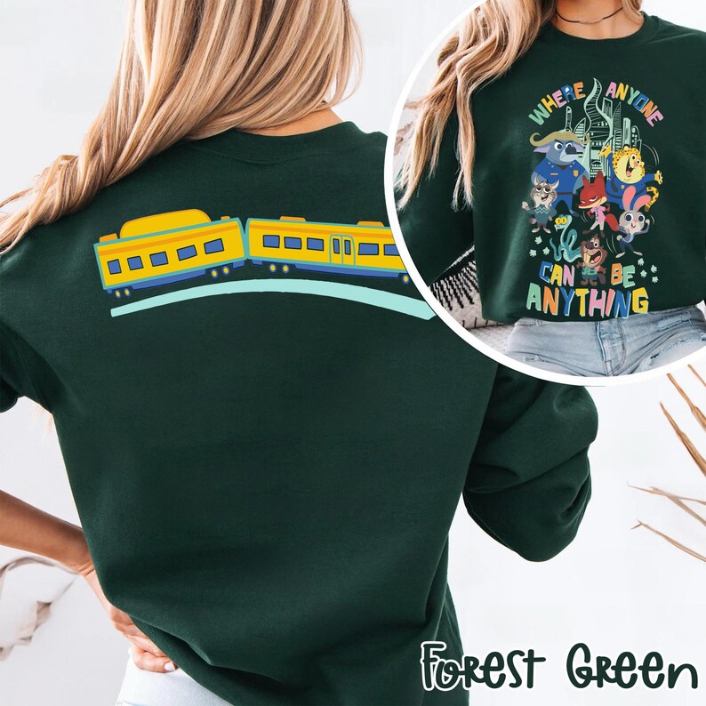 Pu&ograve; includere: Felpa verde foresta con un disegno di treno giallo sul retro. La parte anteriore presenta una grafica colorata con il testo "Where Anyone Can Be Anything".