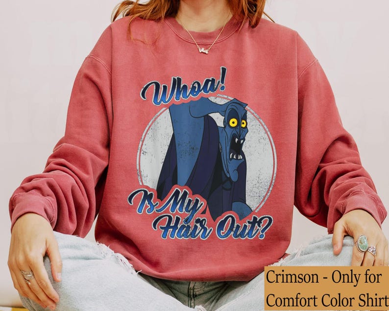 Puede incluir: Sudadera de color carmes&iacute; con un gr&aacute;fico desgastado de un personaje de dibujos animados azul con ojos amarillos. El texto "Whoa! Is My Hair Out?" est&aacute; escrito arriba y abajo del personaje en azul. Es una camiseta Comfort Color.