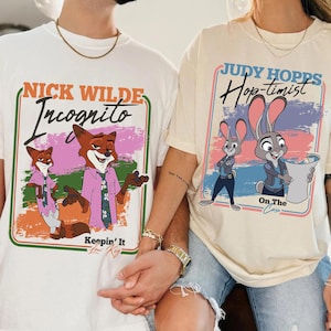 May include: Two t-shirts with cartoon graphics. One is white with a fox graphic and the text "Nick Wilde Incognito". The other is cream-colored with a bunny graphic and the text "Judy Hopps Hop-timist". Both shirts have a retro design.