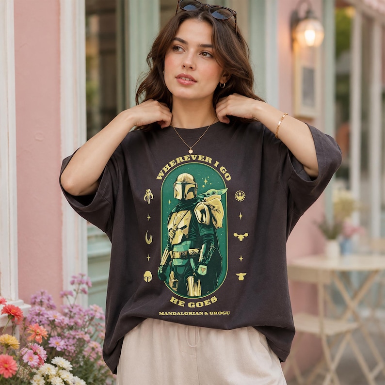 Peut inclure: T-shirt gris fonc&eacute; avec un motif de The Mandalorian et Grogu, et le texte "WHEREVER I GO HE GOES". Le design est dans un ovale vert, avec des accents jaunes et blancs. Coupe ample et d&eacute;contract&eacute;e.